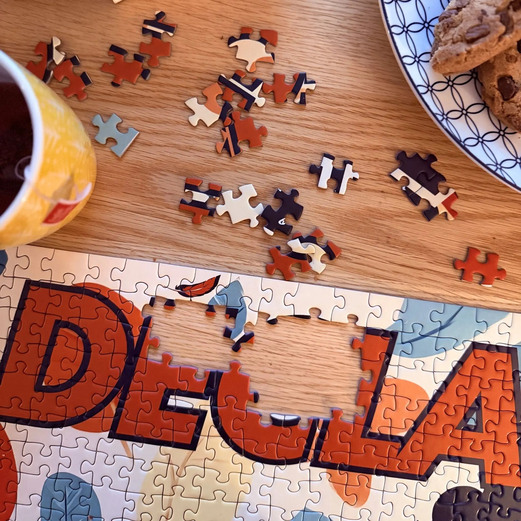 Détail d’un puzzle adulte 1000 pièces DECLARER SA FLEMME ZEBRESQUE sur table en bois avec thé et livre, pensé comme activité calme, anti-stress et sans écran pour les personnes neuroatypiques, TDAH ou en recherche de déconnexion