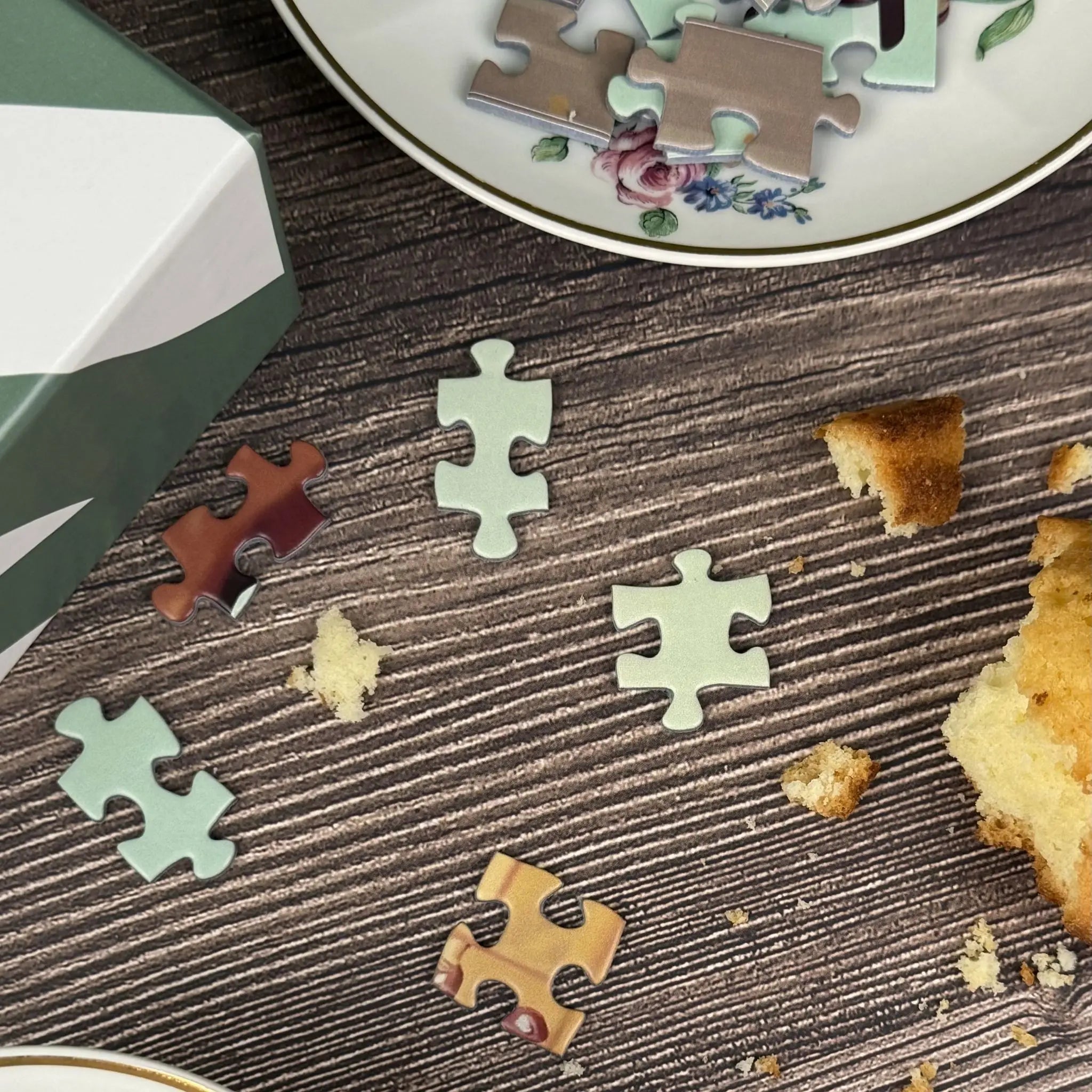 Détail de pièces de puzzle adulte 1000 pièces ZEBRESQUE sur une table en bois avec gâteau et vaisselle vintage, dans une ambiance calme et anti-stress pensée pour la déconnexion et l'appel à la nostalgie