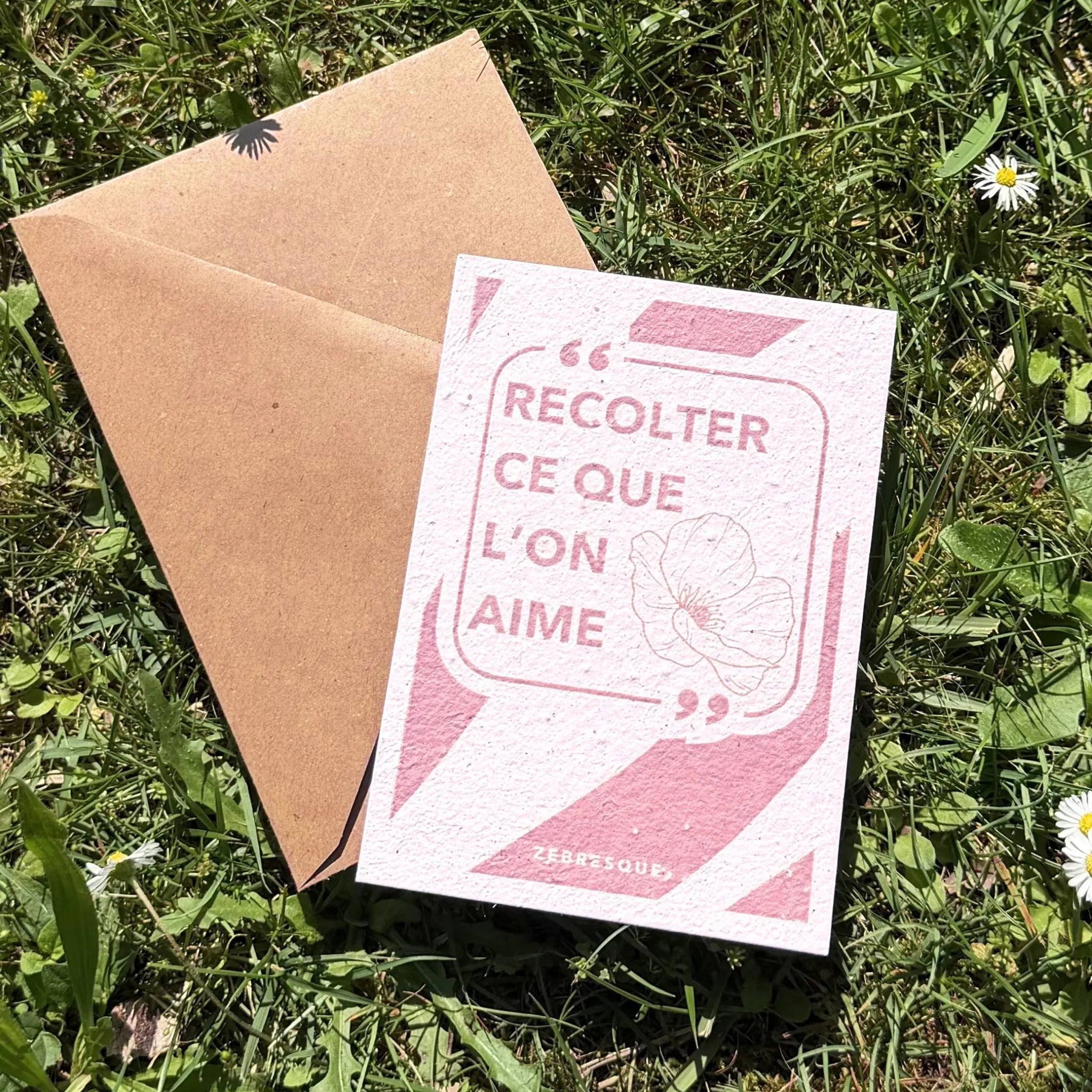 Carte à planter “Récolter ce que l’on aime” avec enveloppe kraft posée dans l’herbe, imprimée sur papier recyclé ensemencé. Papeterie à planter poétique ZEBRESQUE inspirée des petits plaisirs sensibles et des pauses créatives en pleine nature.