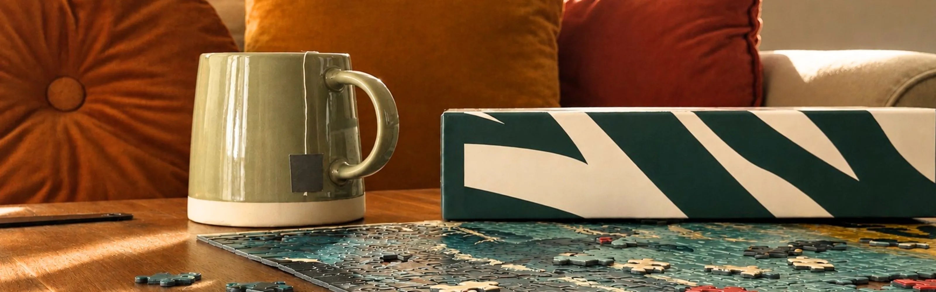 Puzzle adulte ZEBRESQUE en cours d’assemblage sur une table basse avec une tasse de thé dans un salon chaleureux pour s'accorder une pause.